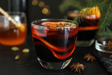 Glass cup of tasty mulled wine on black wooden table