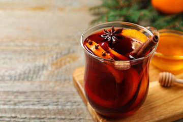 Glass cup of tasty mulled wine on wooden table. Space for text