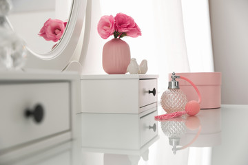 White dressing table with decor and bottle of perfume in room