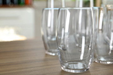 Empty glasses on wooden table against blurred background