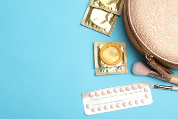 Flat lay composition with birth control pills and condoms on light blue background, space for text....