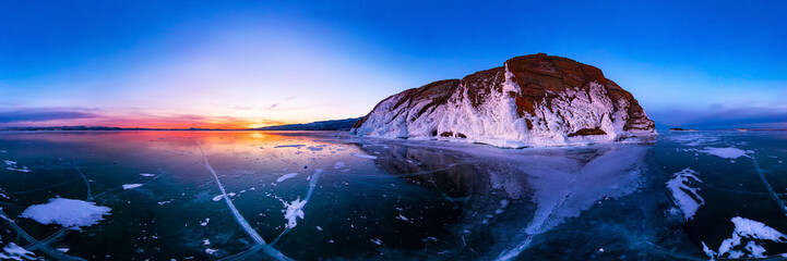 colorful sunset on winter lake Baikal near an island covered with ice. . Cylindrical panorama 360