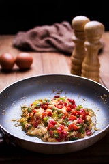 Sauteed vegetables and egg in a pan with kitchen utensils.