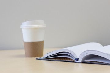 Book turning pages and a paper cup coffee , focus at book