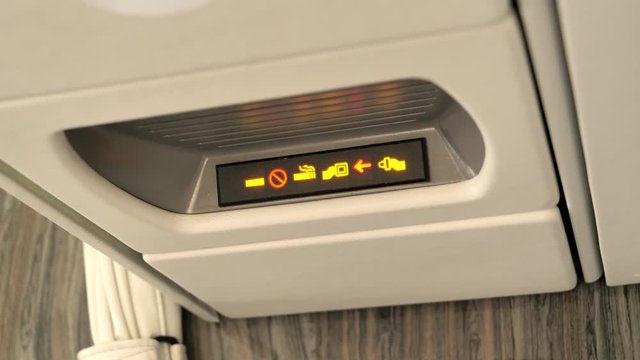 Fasten Seatbelt and No Smoking light coming on for passenger safety in aircraft.