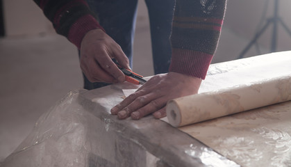 Worker cutting wallpaper. Apartment repair