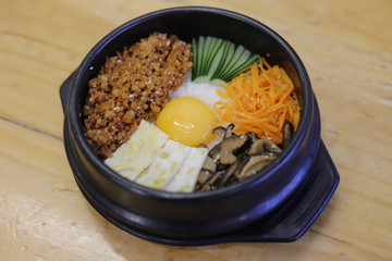 Korean Bibimbap dish with rice and vegetables on wood background.