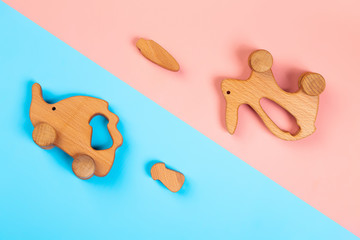Minimalistic flat lay with a wooden toys rabbit with carrot, hedgehog with mushroom  on an isolated multicolored vibrant geometric background. Toy for entertaining children and parents