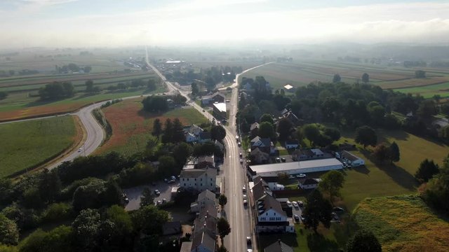 High rising aerial drone shot of fork in road leading out of town in Strasburg Pennsylvania USA