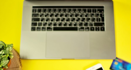 Credit card is placed near laptop, and phones are placed to buy online shopping on yellow...