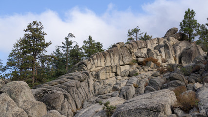 Fototapeta na wymiar diagonal big rocks with pines and clouds