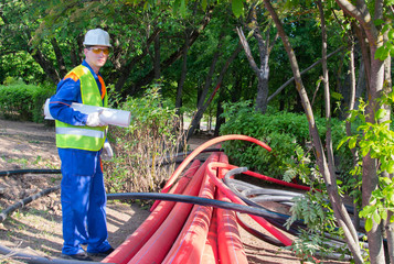 the engineer holds a bundle of paper in his hands, communication schemes for laying plastic pipes, there is a place for inscription
