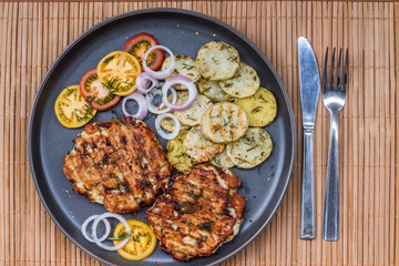 Chopped chicken cutlet with grilled vegetables lie on a plate. Grilled poultry and vegetables. Beautiful food. Food layout.