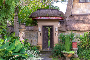 Fototapeta na wymiar The sidewalk leads to a enter in house with Balinese sculptures in a tropical garden, island Bali, Indonesia