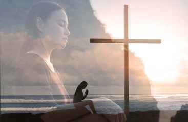 Religious woman praying to god next to a cross, peaceful nature.