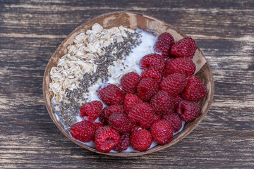 Smoothie in coconut bowl with raspberries, oatmeal and chia seeds for breakfast , close up. The concept of healthy eating, superfood