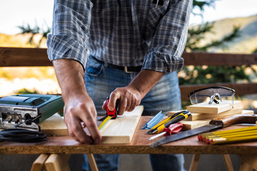 Adult craftsman carpenter with the meter measuring a wooden table. Housework do it yourself. Stock photography.