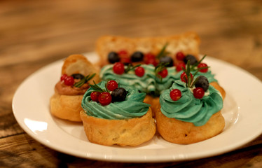 eclairs decorated with fresh berries on a white plate, handmade, culinary theme, close up