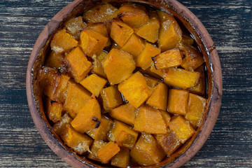 Baked yellow pumpkin with honey, olive oil and spices on a plate on the wooden table. Vegetarian food. Closeup