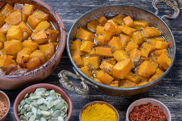 Baked yellow pumpkin with honey, anise, olive oil and spices on a plate on the wooden table. Vegetarian food. Closeup