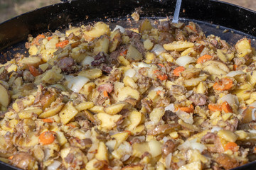 Roast potatoes and meat in a large pan.Young potatoes are fried in oil, street food