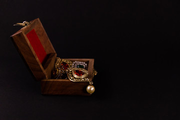 Golden earing set in wooden box on black background