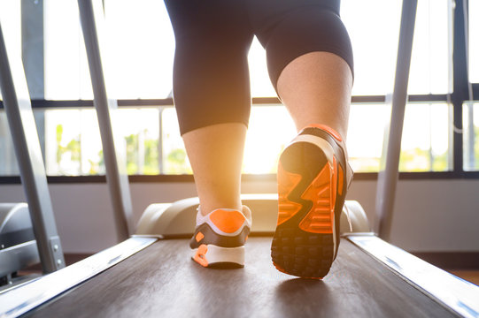 closeup of leg of fat woman being run or jog on belt of treadmill machine