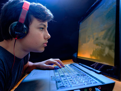 Caucasian Boy playing war games on his laptop