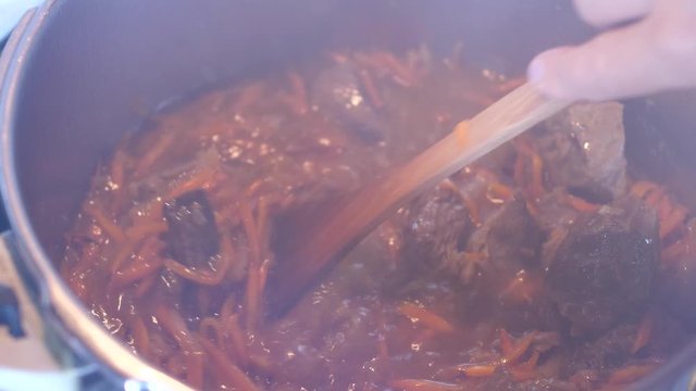 Boiling meat crots with carrots when cooking Plov traditional dish from Uzbekistan