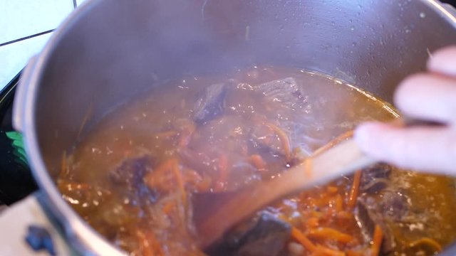 Boiling meat crots with carrots when cooking Plov traditional dish from Uzbekistan
