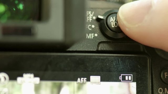 Close clip of photographer changing autofocus setting via a dial on the back of the camera 
