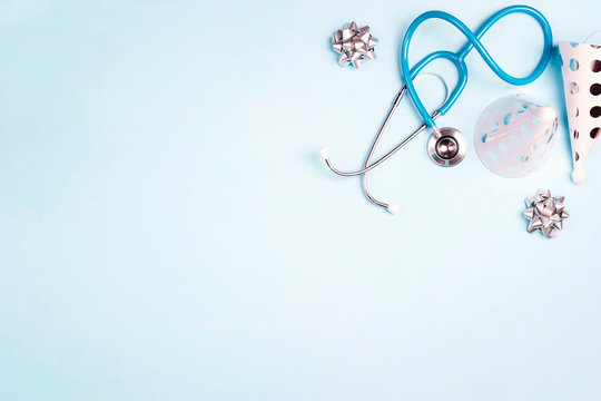 Doctor's day greeting card with stethoscope and festive caps on blue background.