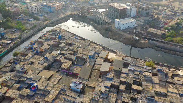 Aerial: Shanties and drainage in slum by sea against sky - Mumbai, India