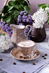 Freshly brewed coffee with a milky foam topped with cinnamon in a brown cup