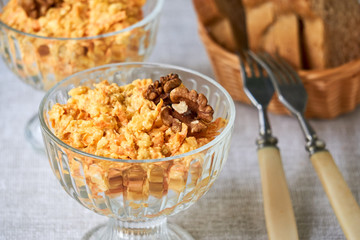 Rice salad with carrots, cheese and walnuts in a glass bowl