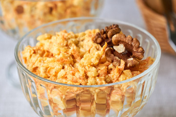 Rice salad with carrots, cheese and walnuts in a glass bowl