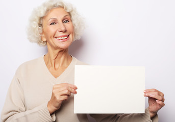 Aged woman with blank advertising board or copy space. Portrait of handsome expressive grandmother.