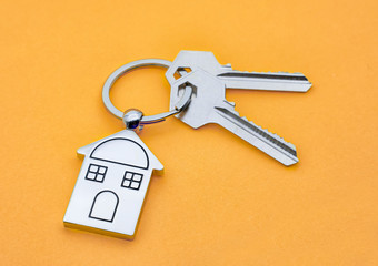 key chain with house symbol and keys on yellow background,Real estate concept