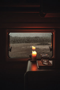 Brennende Kerze vor einem Fenster mit Regentropfen in einem Camper Van