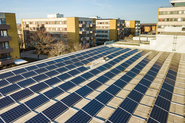 Aerial view of blue shiny solar photo voltaic panels system on commercial roof producing renewable...