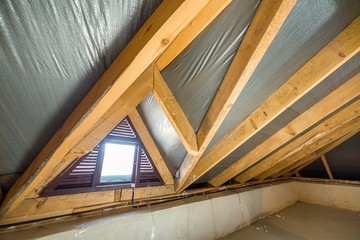 Fototapeta premium Attic of a building with wooden beams of a roof structure and a small window.
