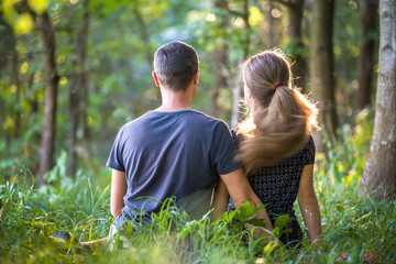 Youg couple, man and a woman sitting together outdoors enjoying nature.