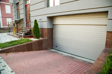 Close up view of part of a building facade with garage door and the surface of granite wall. Natural stone materials.
