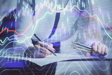 Fototapeta na wymiar Double exposure of hands making notes with forex chart huds. Stock market concept.