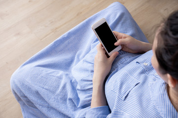 pregnancy, motherhood and expectation concept, pregnant woman using mobile on wood floor, top view.