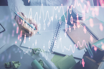Obraz premium Financial forex graph displayed on hands taking notes background. Concept of research. Multi exposure