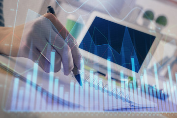 Financial forex graph drawn over hands taking notes background. Concept of research. Double exposure