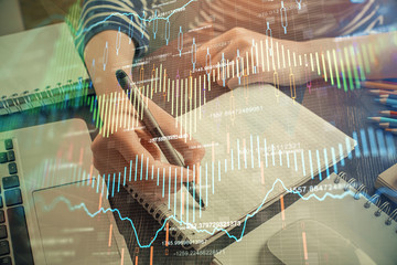 Financial chart drawn over hands taking notes background. Concept of research. Double exposure