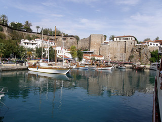 Fototapeta na wymiar Sea Bay with blue water and white boats along the pier on the background of the stone walls of the ancient fortress