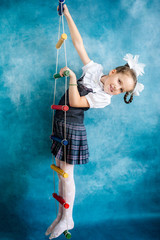 Portrait of a girl in a school uniform hanging on a rope ladder.